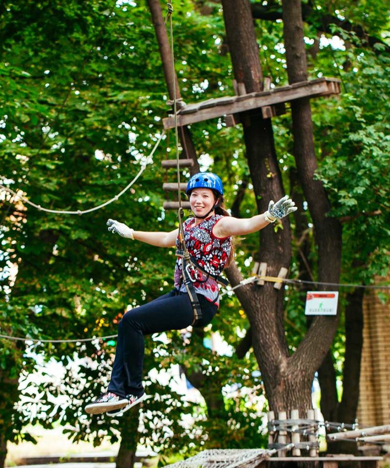 Femme sur une tyrolienne du parcours accrobranche adultes