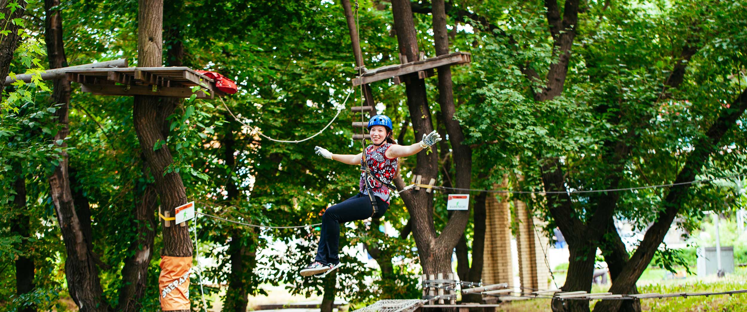 Femme sur une tyrolienne du parcours accrobranche adultes