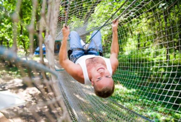 Homme dans un filet du parcours accrobranche adultes