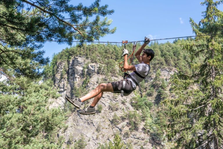 garçon suspendu à la tyrolienne du parcours d'accorbranche