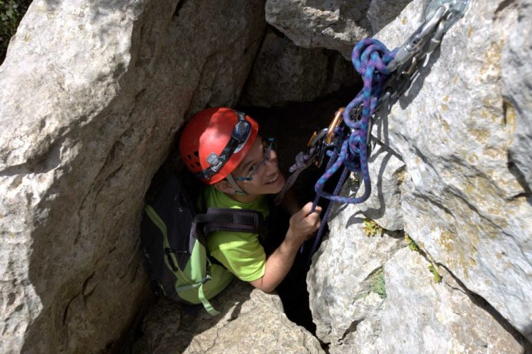 Jeune homme à la sortie d'un passage étroit du parcours aventure du Pic Saint Loup