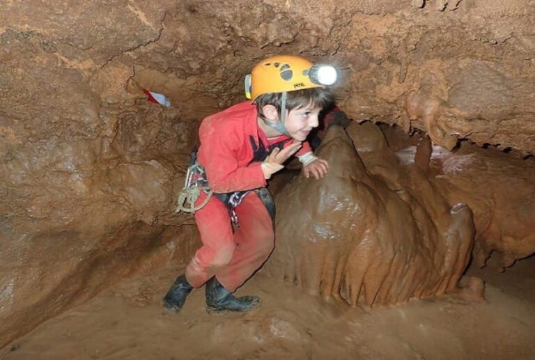 un jeune garçon sortant d'un passage étroit du parcours des grottes aurélie et du maire